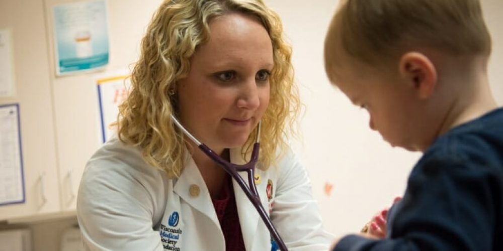 A doctor is using a stethoscope on a young child