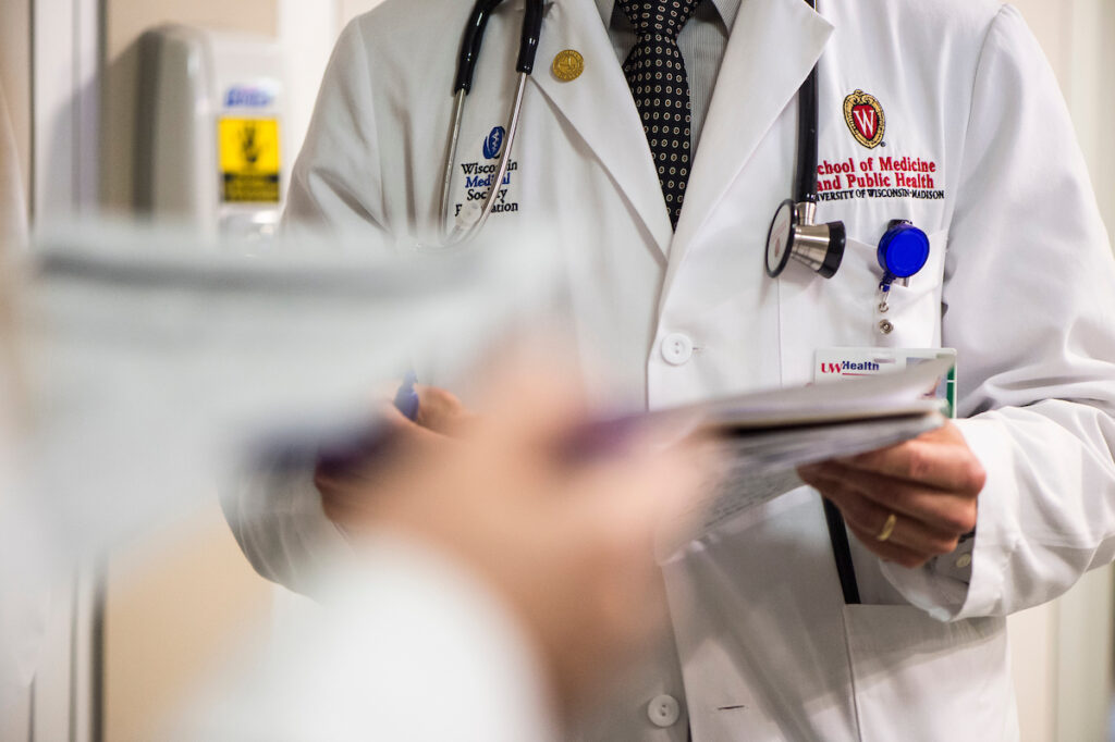 An embroidered W crest is pictured on a medical student’s white coat during floor rounds.