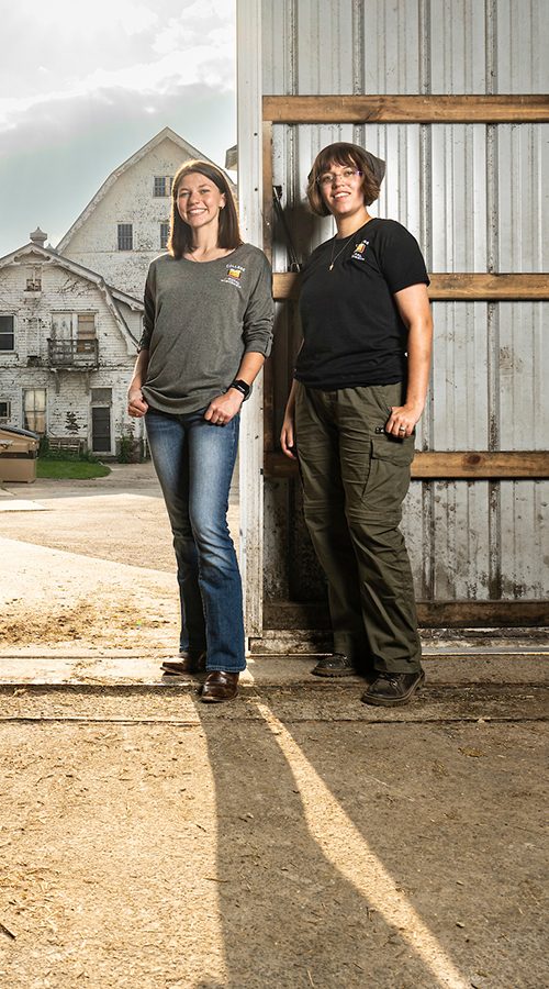 Two undergraduate students stand just inside the door of a dairy barn on the campus of UW–Madison