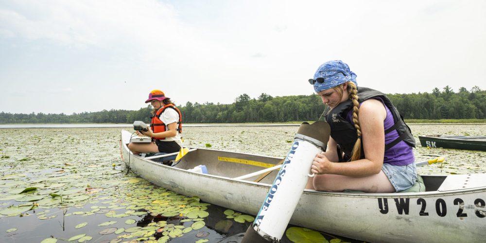 Two UW–Madison students in a canoe collect data from Allequash Lake