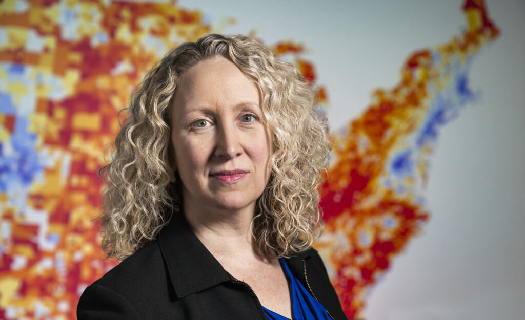 Dr. Amy Kind stands in front of a colorful map showing neighborhood-level data.