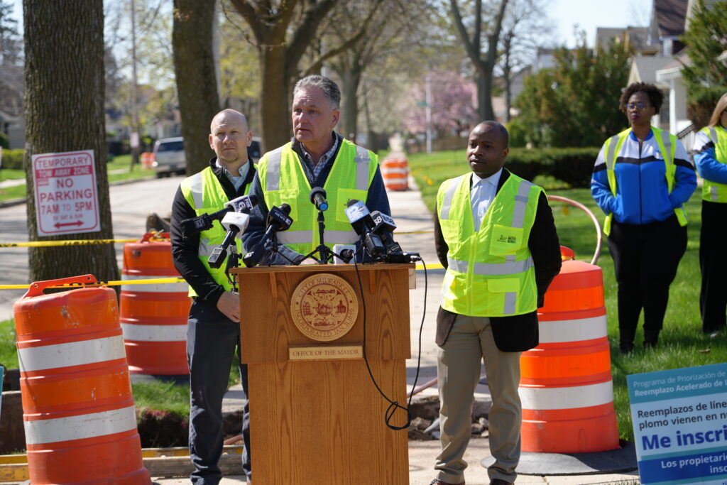 Patrick Pauly speaks at a podium during a Milwaukee Water Works press event near a lead service line replacement construction site.