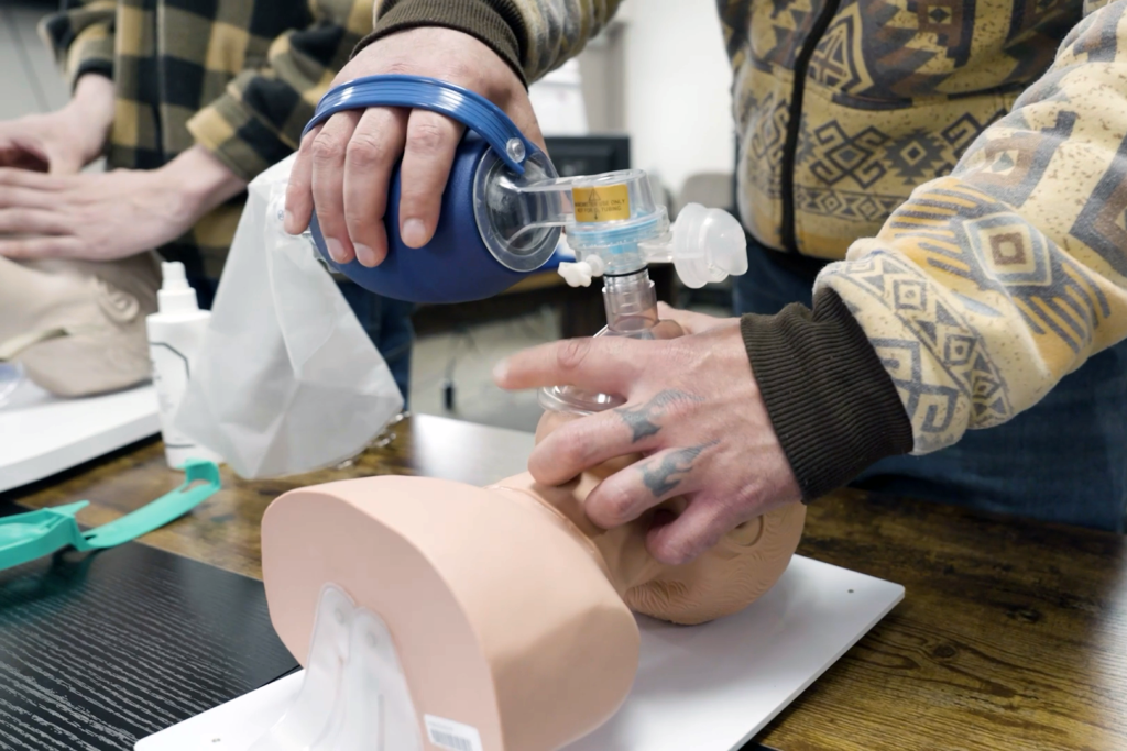 Close-up of a man's hands working with a dummy patient