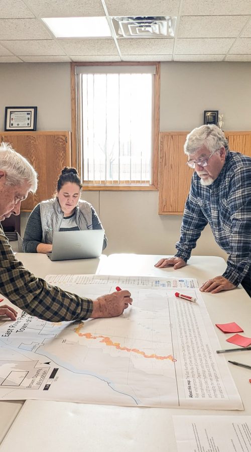 A group of people father around a map.